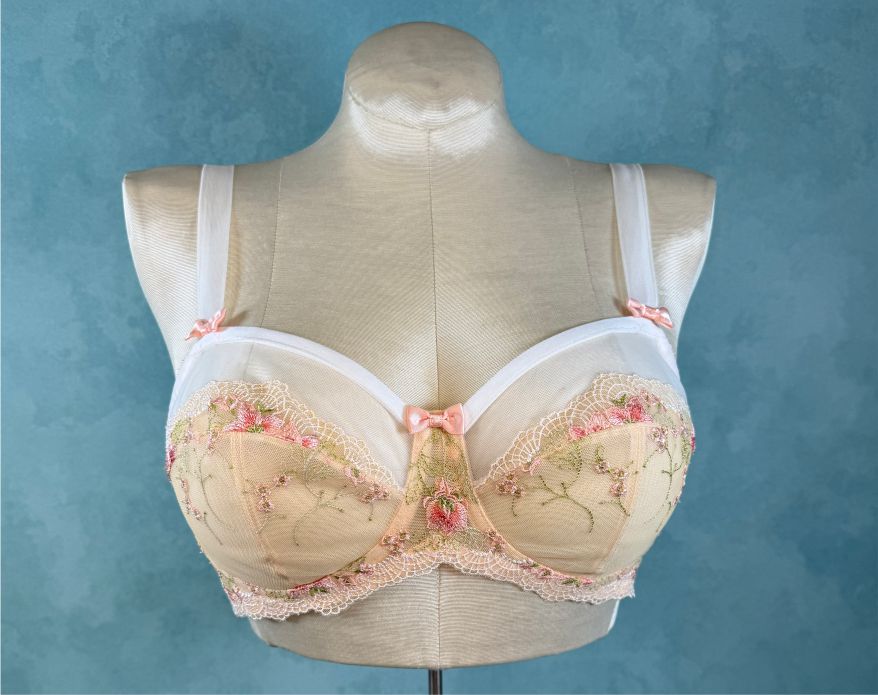 Beige bra with floral lace details on a mannequin against a blue background